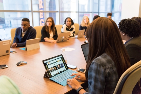 Colleagues sitting around a conference table with laptops