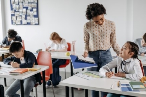 Student looking up at her teacher from her desk