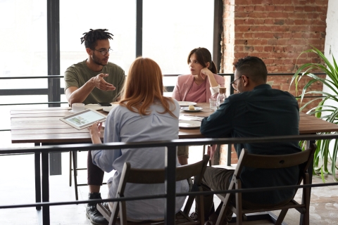 four people sitting around a table talking