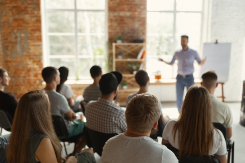 Person standing in front of a room of seated listeners